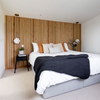 White bedroom with wood wall panelling, white bedding with grey throw