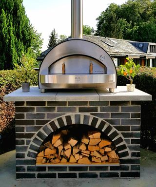 A brick built stand for a pizza oven with a space for logs