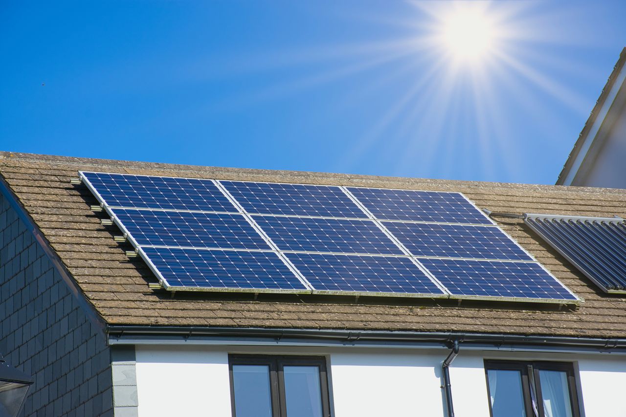 house rooftop with solar panels on it under the sun against a blue sky