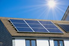 house rooftop with solar panels on it under the sun against a blue sky