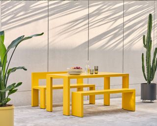 A bright yellow outdoor dining table and bench seats made from weather-resistant aluminium