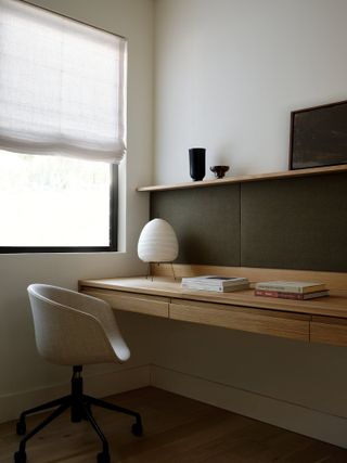 home office with built-in desk, roman blinds, paper lantern lamp and pinboard backing