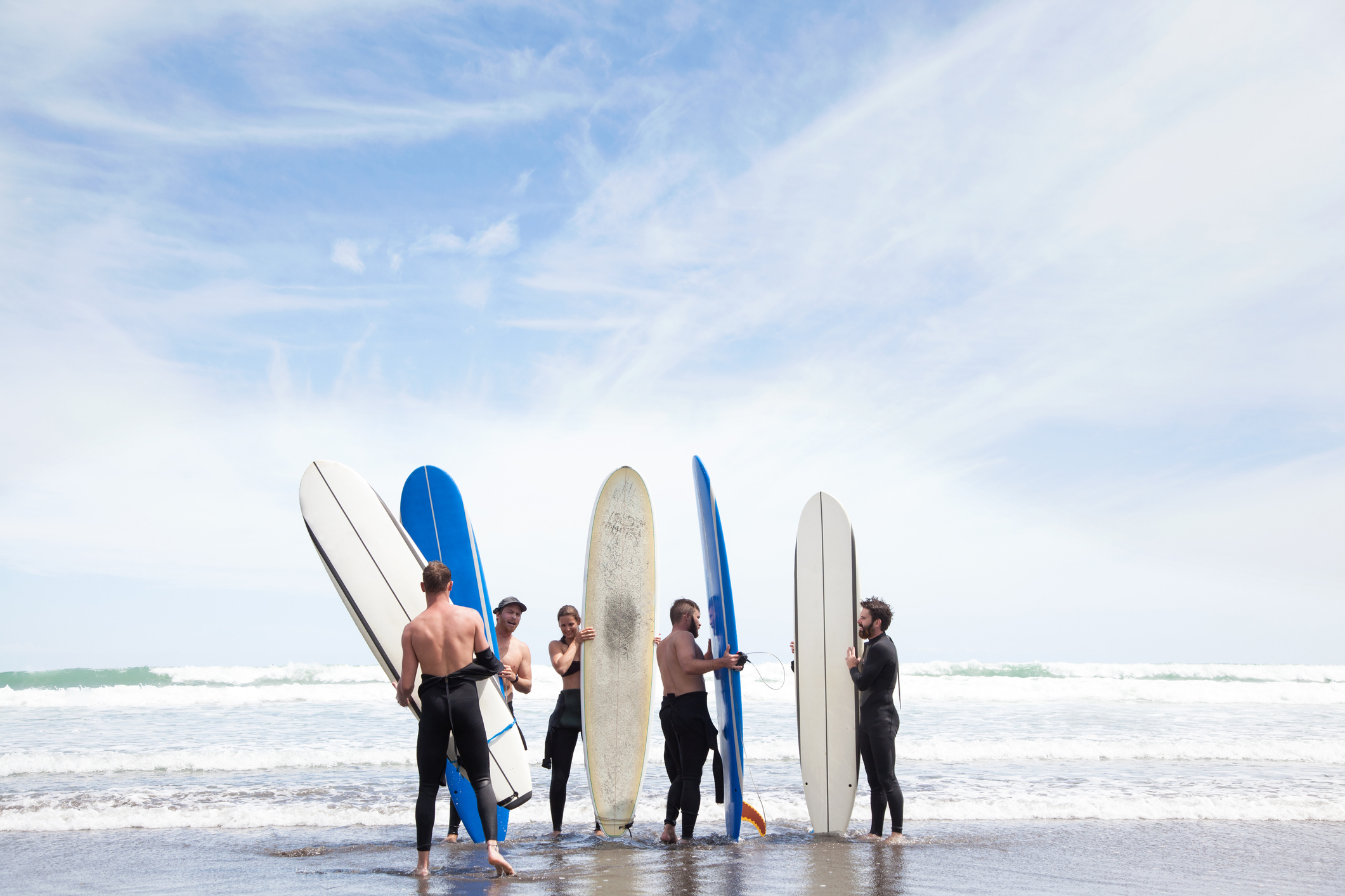 A group of men and women surfing, or taking a surfing class.