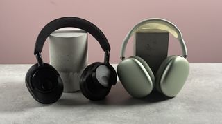 The Cambridge Audio Melomania P100 and AirPods Max propped up in front of a pink background.