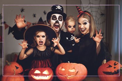 To celebrate Halloween, a family dress up in spooky costumes and stand behind carved pumpkins