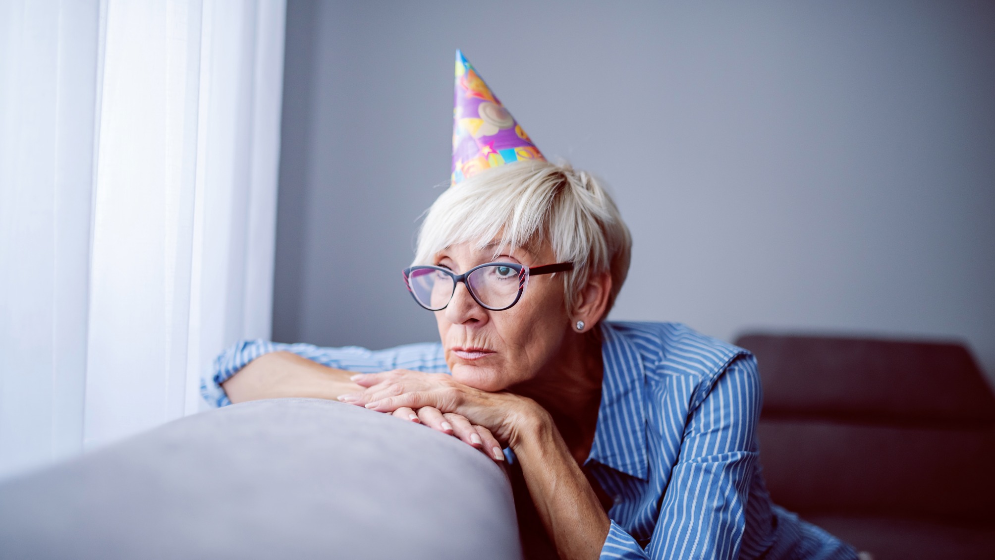 Sad senior woman wearing party hat