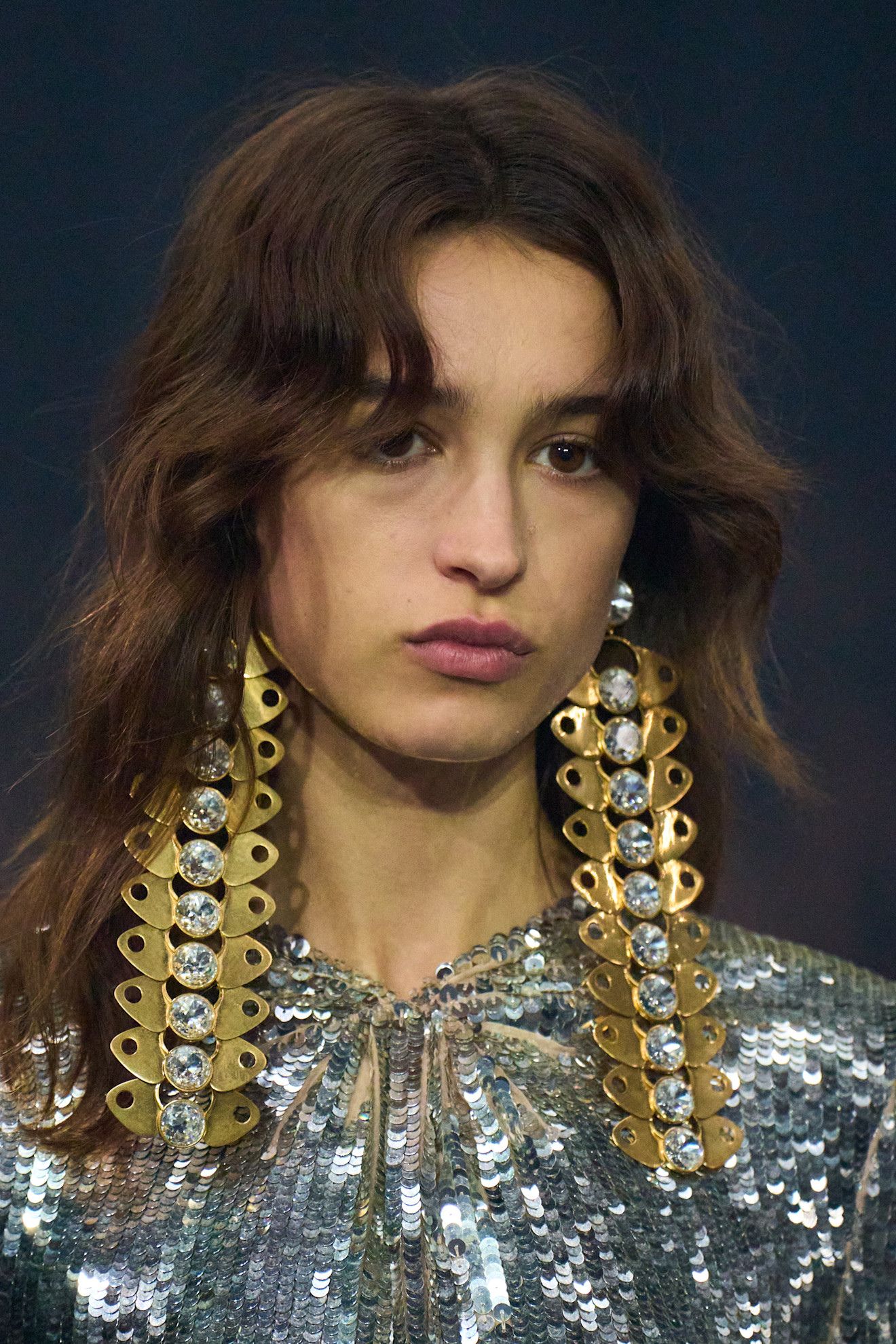 A model at the SS26 Valentino Paris show wearing oversized earrings with curtain bangs