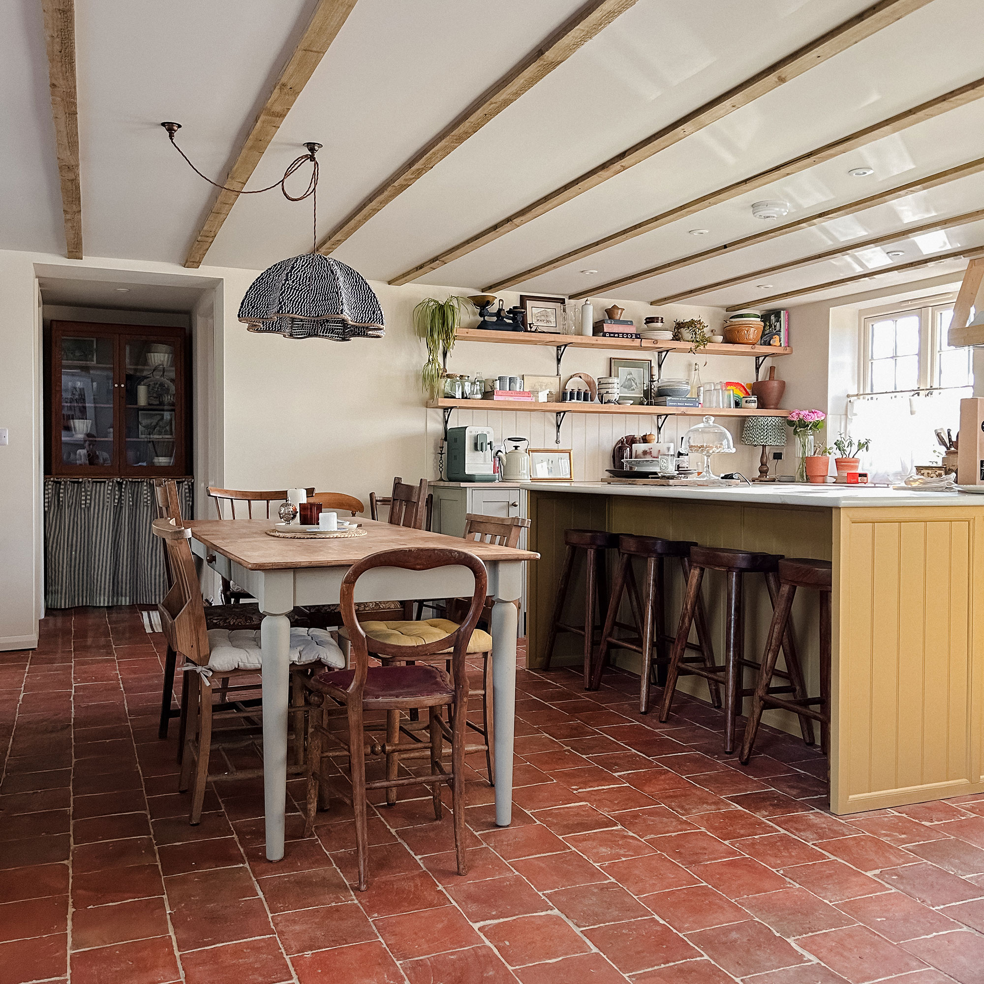 Open plan kitchen diner with mustard island and wooden ceiling beams