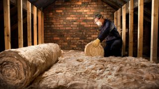 man installing rolls of insulation in loft