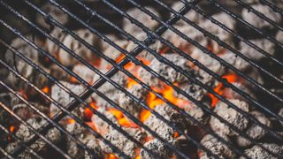 A hot charcoal grill with dirty grates