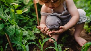 Child kneeling down, playing in the dirt. 