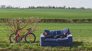 Cyclist naps on a sofa next to his bike