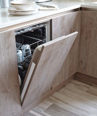 Open dishwasher door in wood cabinets