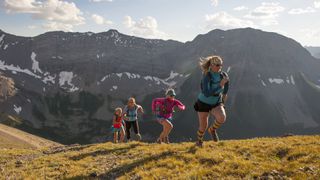 A group of women trail running up a steep mountain