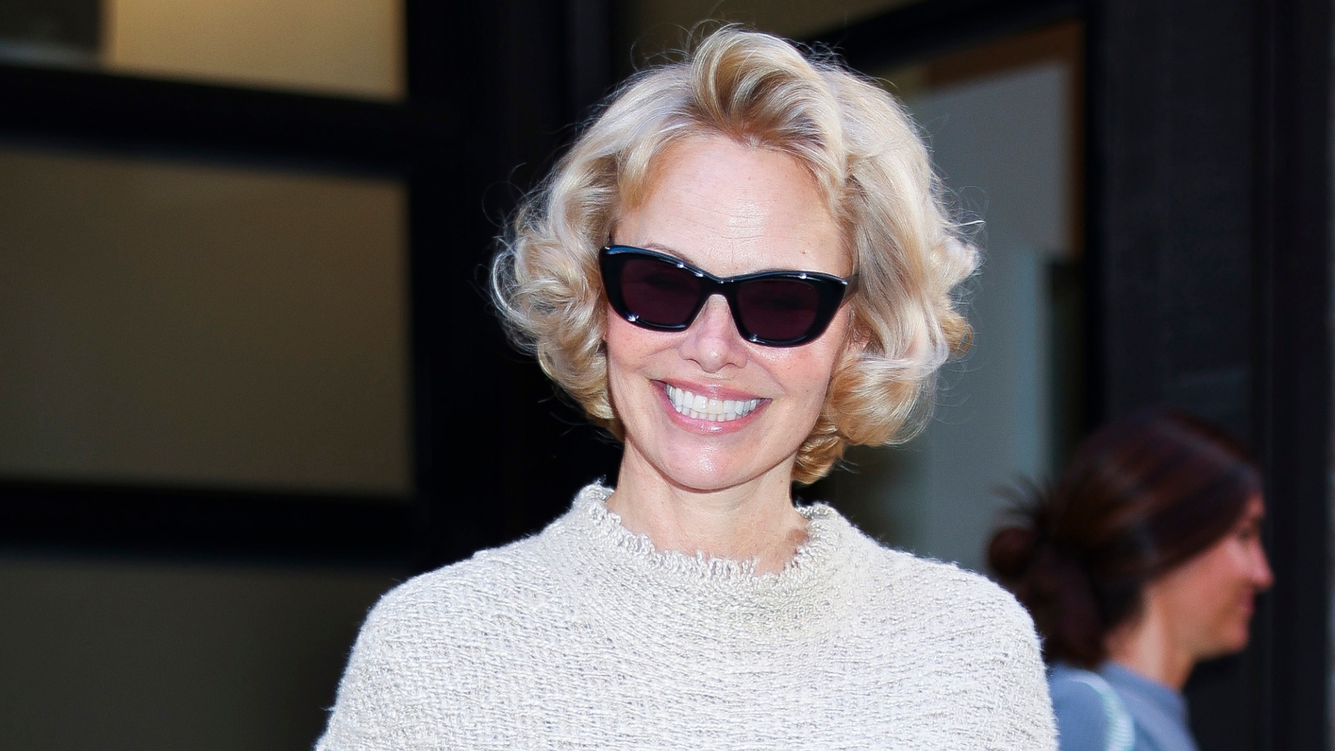 Pamela Anderson is pictured smiling, with a wavy bob hairstyle and wearing black sunglasses in the Meatpacking District on May 20, 2025 in New York City.
