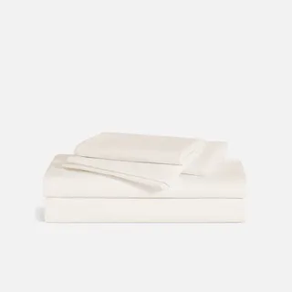 A set of folded cream bed sheets on a white background