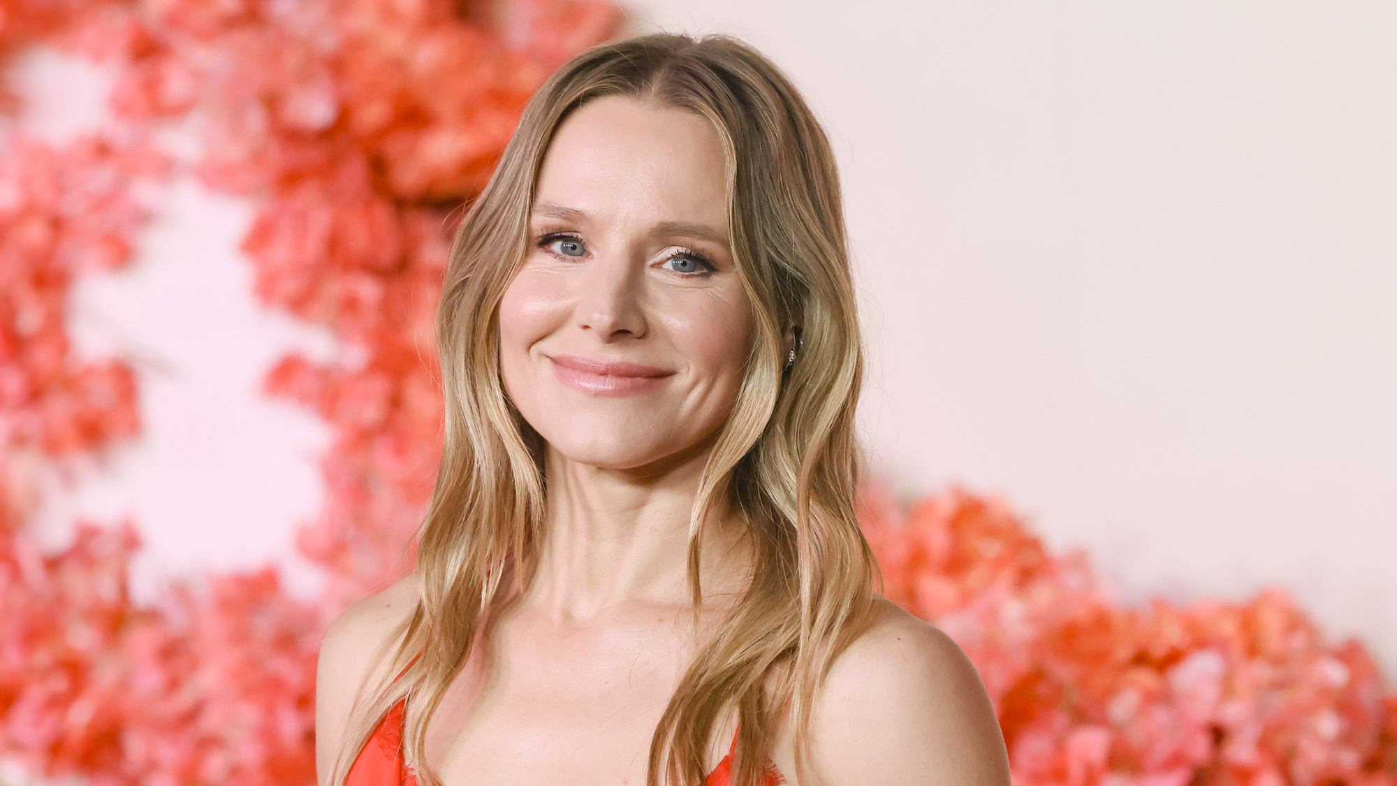 Kristen Bell attends the premiere of Netflix's "Nobody Wants This" Season 2 wearing red dress in front of floral display