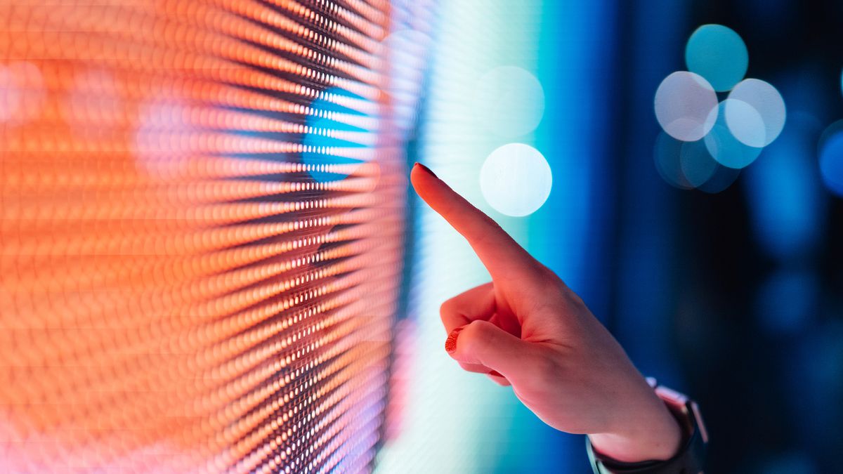 Cloud up of a female hand touching an illuminated digital display in the dark