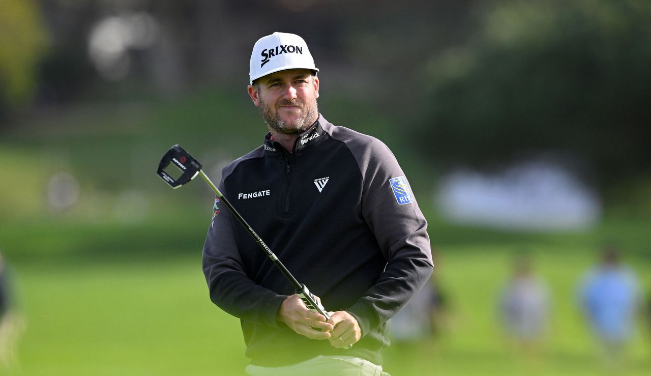 Taylor Pendrith watches his putt on the green whilst wearing a black hoodie