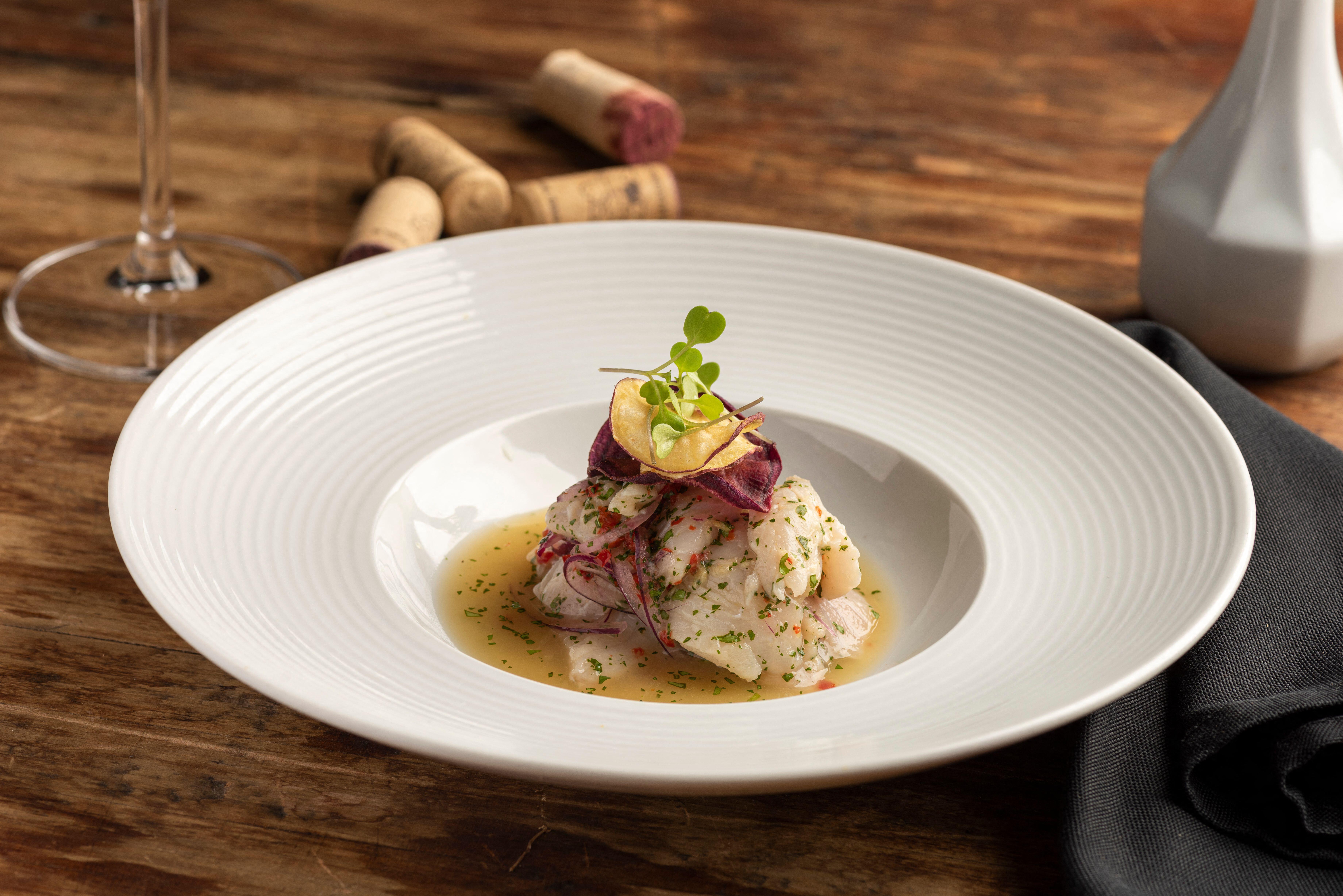Fish seafood ceviche cebiche on a wooden table and wine glass and corks, typical dish from Peru.