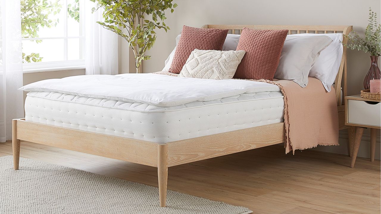 A mattress topper on top of a mattress on a wooden bed frame