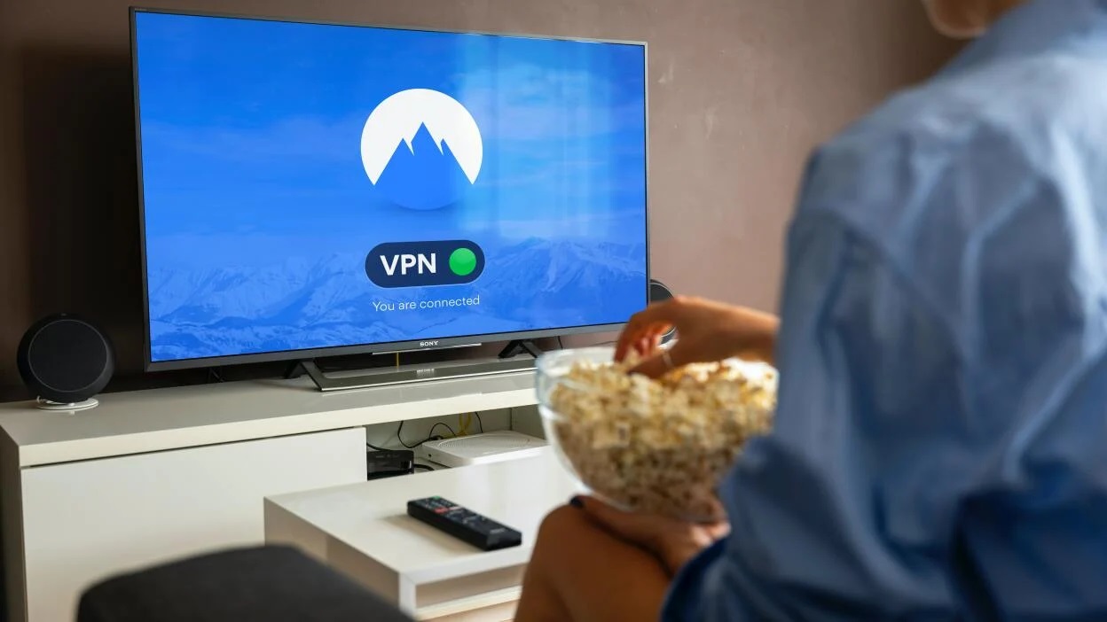 NordVPN en mand spiser popcorn foran en computer med et NordVPN-logo på skærmen