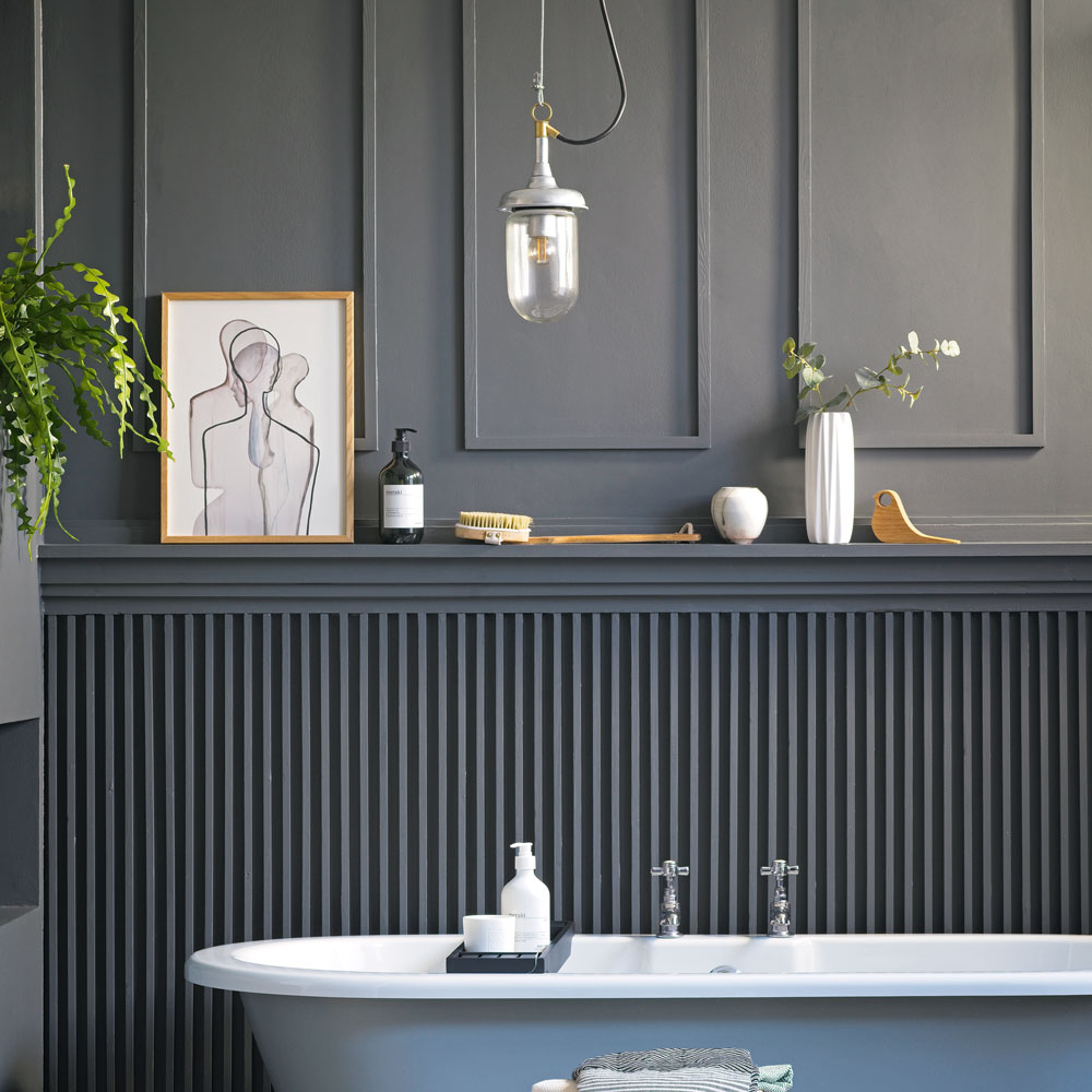 bathroom with wall paneling with bathtub