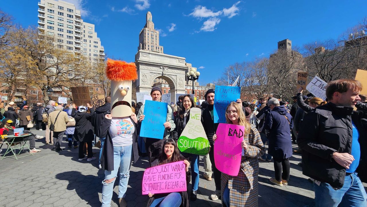 A group of people hold up protest signs at the Stand Up For Science rally