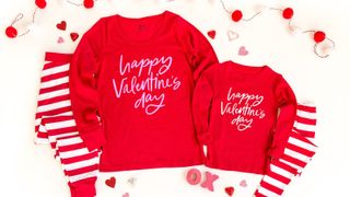 flat lay image of child and adult red pajamas with slogan Happy Valentine's Day written on them
