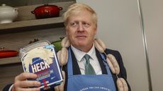 Boris Johnson poses with a string of sausages called "Boris Bangers" during a visit to Heck Foods.