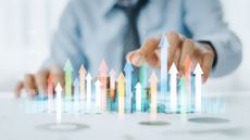 Business man moves hand toward coin stack with data graphics overlayed on top