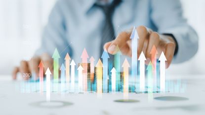 Business man moves hand toward coin stack with data graphics overlayed on top