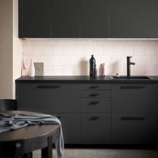 kitchen with black cabinet and white tiles on wall