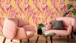 Yellow wallpaper with pink feathers on it on a wall against two pink chairs and a coffee table