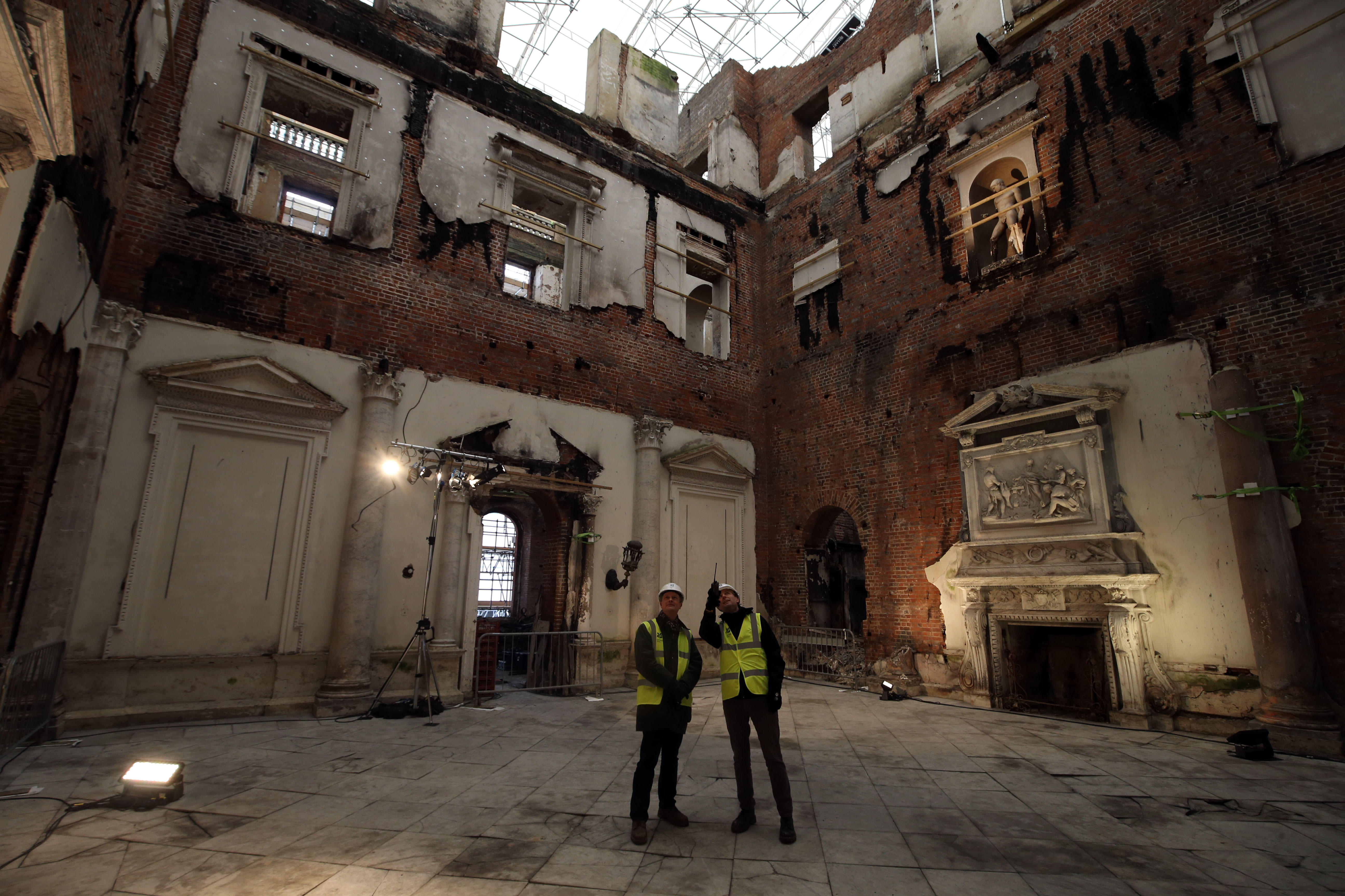 Two men inside the burnt interiors of Clandon Park assess the damage