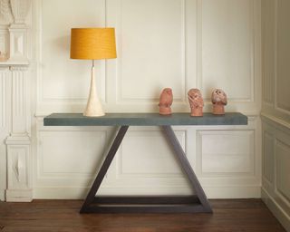 Julian Chichester console table on wooden floor with large table lamp and sculptures