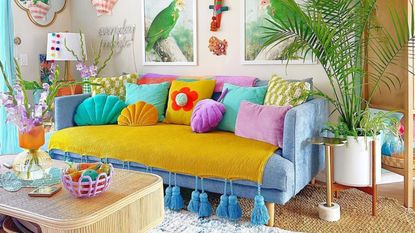 Colorful small living room ideas like this are the goal, with its blue couch and multi-hued throw pillows, art work and bright decorative touches
