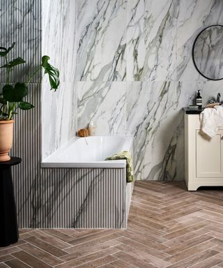 wood effect tiles laid in herringbone pattern, grey, green and white marbled walls and bath panel