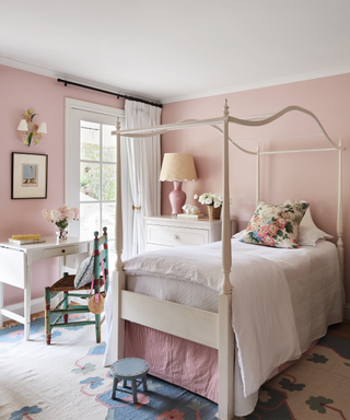 pink bedroom with single four poster bed and pink walls and patterned rug