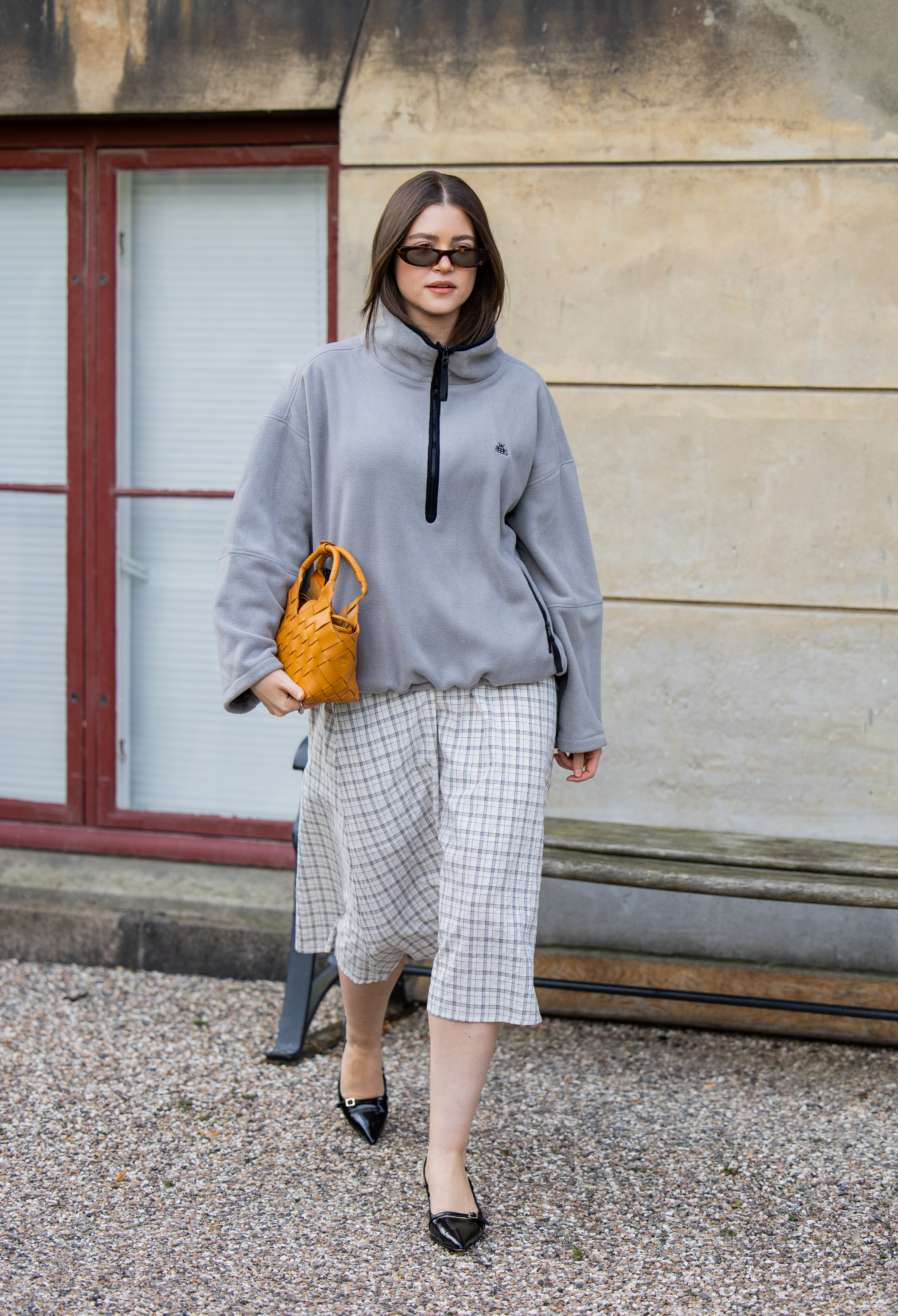 woman wearing a quarter zip, a skirt, and heels