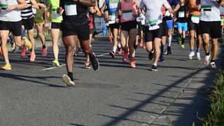 A crowd of people running a road race, shown from the waist down