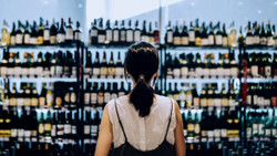 A woman standing in front of shelves filled with wine, beer and spirit bottles