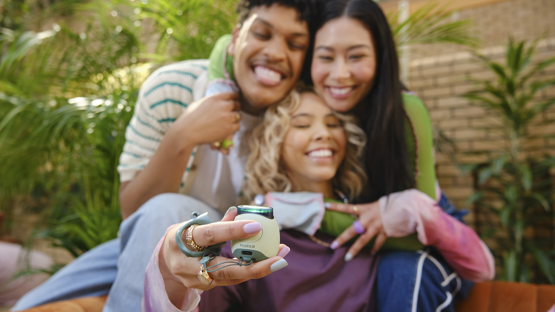 Three people posing for a selfie with the Fujifilm Instax Pal in the foreground