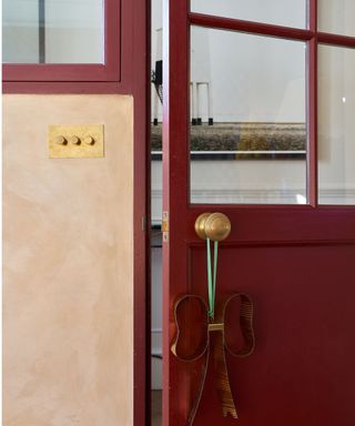 burgundy painted internal glazed door with plaster walls and brass switches and sockets