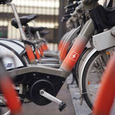 A row of e-bikes in a bike rack with the power symbol on the frame