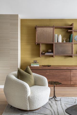White fluffy armchair, yellow and stone coloured wallpaper