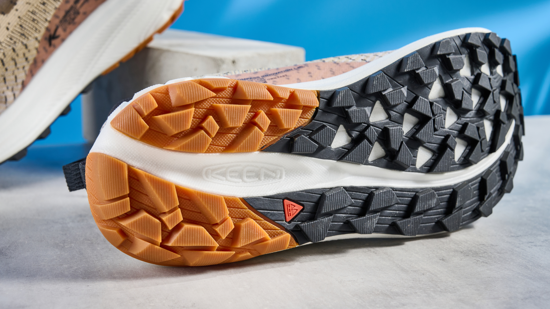 the keen seek trail shoes in brown, black, and beige photographed against the blue tom's guide background
