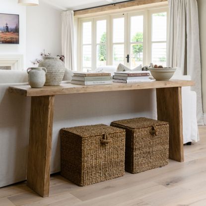Console table in a living room with two wicker baskets sitting on the floor underneath it