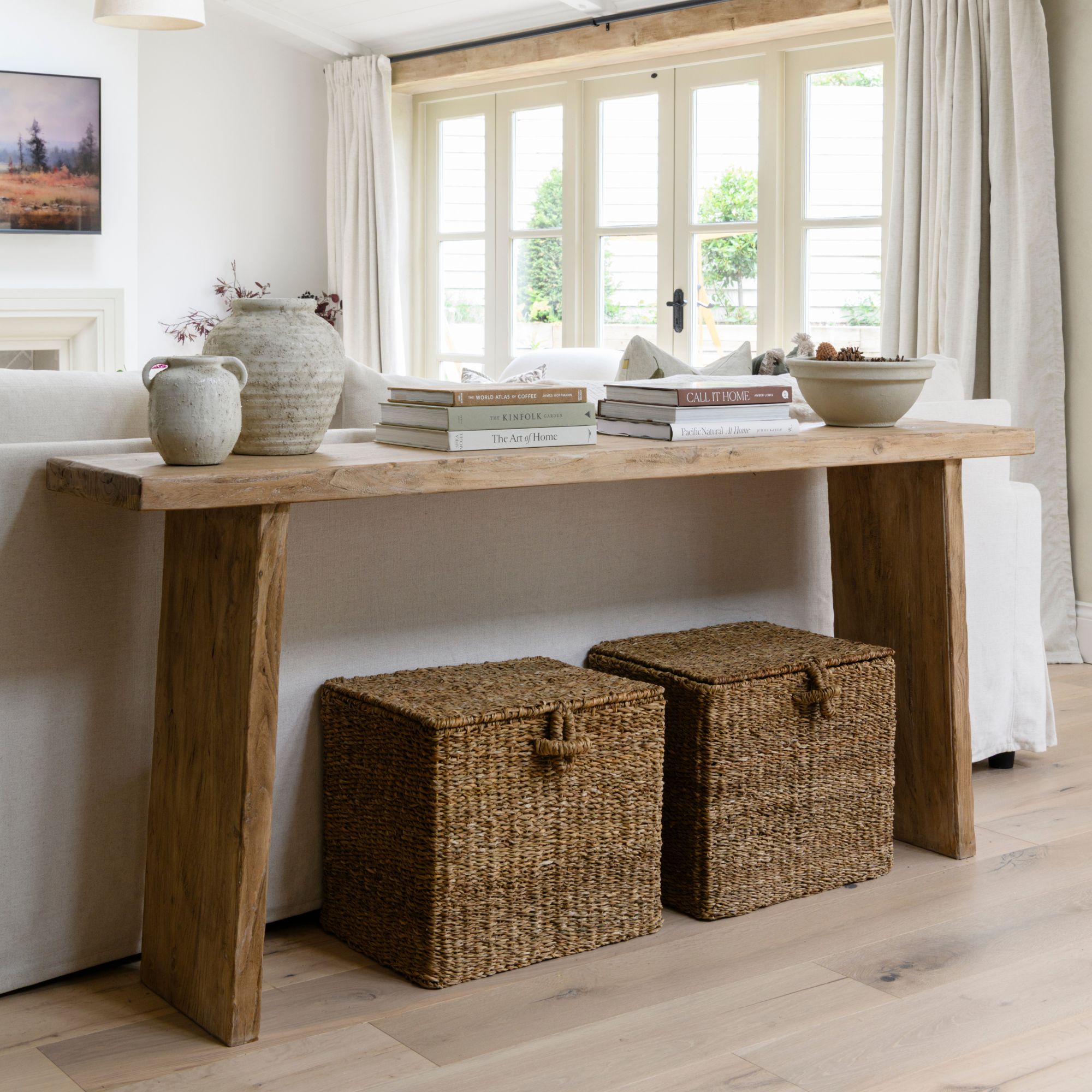 Console table in a living room with two wicker baskets sitting on the floor underneath it