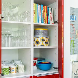 kitchen cabinets with white sections red door and cups books glasses in it